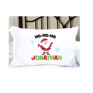 May include: White pillowcase with a red and white Santa Claus illustration, the text "HO-HO-HO" and the name "JONATHAN" in green letters.