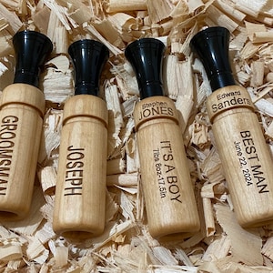 May include: Four wooden whistles with black plastic tops. The whistles are engraved with names and text, including "Groomman", "Joseph", "Stephen Jones", "It's a Boy 7lbs 8oz-17.5in", "Edward Sanders", and "Best Man June 22, 2024".
