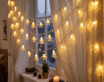 Puede incluir: Una guirnalda de luces LED de color blanco cálido con formas alternas de copos de nieve y árboles de Navidad de plástico transparente, dispuesta en varias filas horizontales sobre una cortina blanca.
