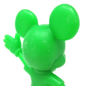 May include: A green plastic figurine of Mickey Mouse with his arms raised. The figurine is facing away from the camera.