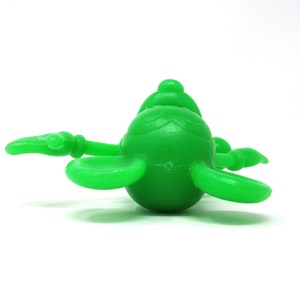 May include: A bright green plastic toy shaped like a cartoon character with large ears and a round body.