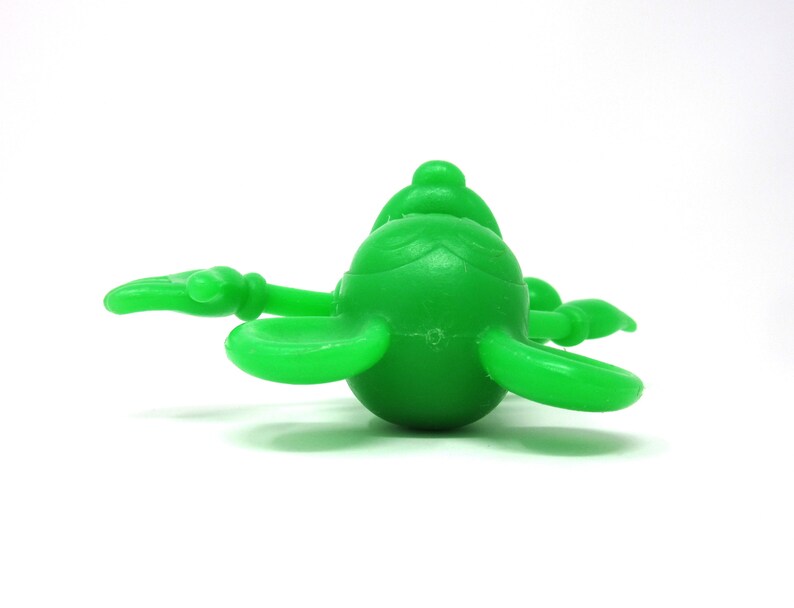 May include: A bright green plastic toy shaped like a cartoon character with large ears and a round body.