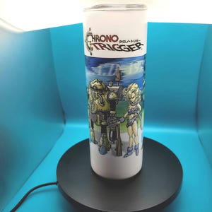 May include: White stainless steel tumbler with a graphic of characters from the video game Chrono Trigger. The text "Chrono Trigger" is printed on the tumbler in Japanese and English.