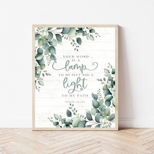May include: A framed print with a white wood background and green eucalyptus leaves. The print features a quote from Psalm 119:105, "Your word is a lamp to my feet and a light to my path."