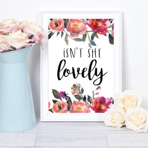 May include: White framed print with watercolor floral border and the text "Isn't she lovely" in black.