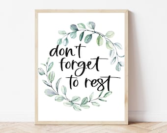 May include: A framed print with a watercolor wreath of green leaves and the text "don't forget to rest" in black calligraphy.