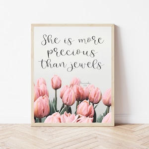 May include: A framed print with a pink tulip floral background and the text "She is more precious than jewels" with the scripture reference "Proverbs 2:15".