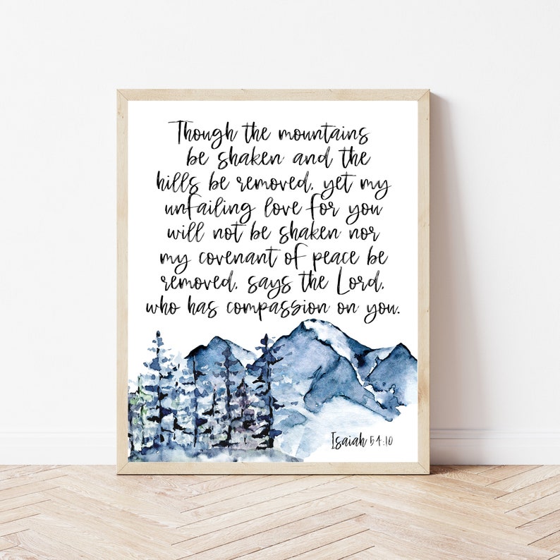 Pu&ograve; includere: Una stampa incorniciata con un acquerello di montagne e alberi blu. L'opera d'arte include il testo "Though the mountains be shaken..." da Isaia 54:10, scritto in elegante calligrafia. La cornice &egrave; di colore legno chiaro.