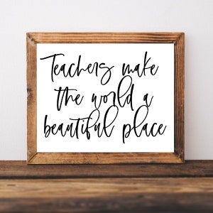 May include: A framed sign with the text "Teachers make the world a beautiful place" in black cursive writing on a white background.