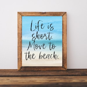 May include: A framed print with a watercolor background of a beach scene. The print features the text "Life is short. Move to the beach."
