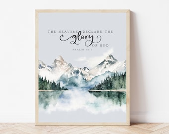 May include: A watercolor painting of a mountain range with a lake in the foreground. The sky is a light blue and the mountains are a light gray with white snow on the peaks. The lake is a light blue and there are trees on the shore. The text "THE HEAVENS DECLARE THE GLORY OF GOD PSALM 19:1" is written in black at the top of the image.