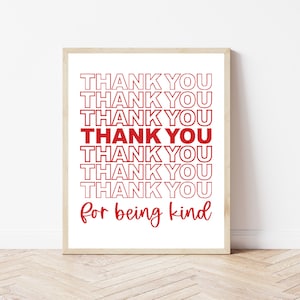 May include: A white framed print with the text "THANK YOU" repeated seven times in red, followed by "for being kind" in red cursive writing.