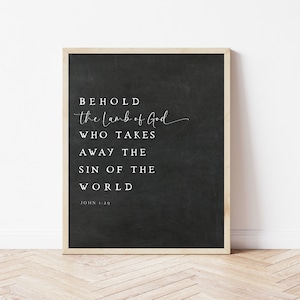 以下が含まれることがあります： 黒板の背景に白黒のタイポグラフィー印刷が施され、テキスト「BEHOLD the Lamb of God WHO TAKES AWAY THE SIN OF THE WORLD JOHN 1:29」が書かれています。