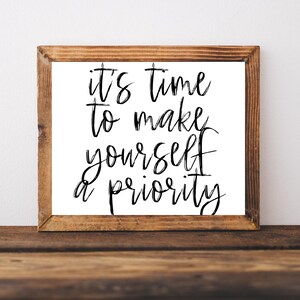 May include: A framed print with a white background and black calligraphy text that reads "it's time to make yourself a priority".