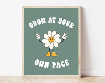 Op de afbeelding: Een groene poster met een witte madeliefje met een geel smiley-gezicht en de tekst "GROW AT YOUR OWN PACE" in wit met een retro-lettertype.