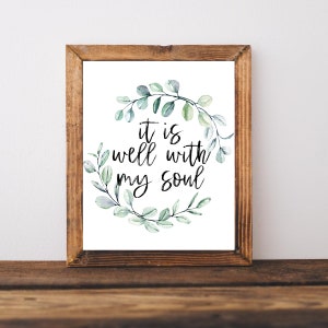 May include: A framed print with a watercolor wreath of eucalyptus leaves surrounding the text "it is well with my soul".