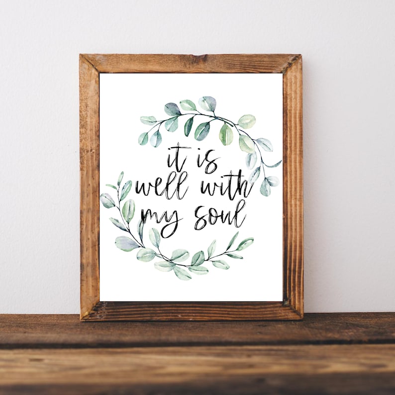 May include: A framed print with a watercolor wreath of eucalyptus leaves surrounding the text "it is well with my soul".