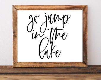 May include: A wooden framed sign with white background and black calligraphy text that reads "go jump in the lake".