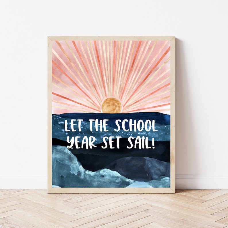 May include: A framed print with a watercolor painting of a sunrise over a blue ocean. The text "Let the school year set sail!" is written in white on the ocean.