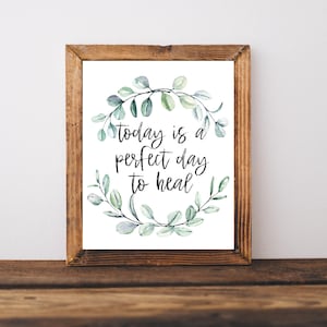 May include: A framed print with a white background and a green watercolor wreath. The text inside the wreath reads "today is a perfect day to heal".