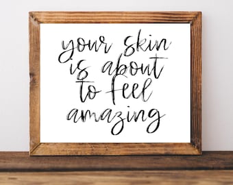 May include: A framed sign with the text "your skin is about to feel amazing" in black script font on a white background.