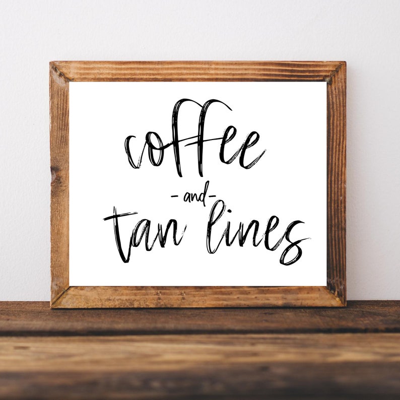May include: A framed sign with the text "coffee -and- tan lines" in black script font on a white background.