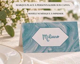 Peut inclure: Un marque-place en papier plié avec un motif marbré bleu sarcelle et blanc, doté d'un hexagone central blanc portant le nom Miliano en écriture cursive. Le texte MARQUE-PLACE À PERSONNALISER SUR CANVA et MODÈLE NUMÉRIQUE À IMPRIMER est visible.