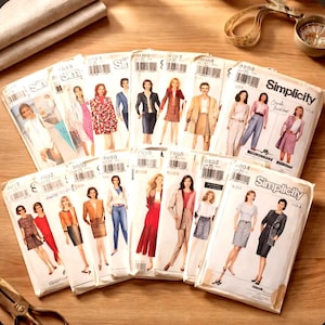 May include: A collection of vintage Simplicity sewing patterns featuring illustrations of women's fashion designs. The patterns showcase various styles, including dresses, skirts, and jackets, with a retro aesthetic. The patterns are arranged on a wooden surface.