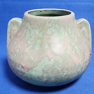 May include: A green and pink ceramic vase with two handles. The vase has a crackled glaze and a mottled appearance.