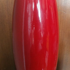 Peut inclure: Un vase en céramique rouge brillant et haut, de forme arrondie.