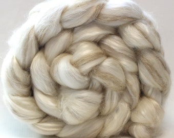 May include: A close-up of a white and beige fiber blend, twisted into a circular shape. The fiber is soft and fluffy, and appears to be a natural material.