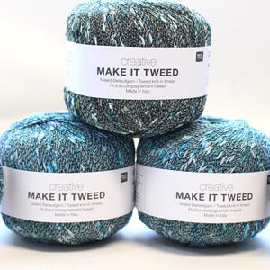 May include: Several balls of yarn are stacked and arranged in a row. The yarn is a mix of teal, green, and white. Each ball has a white label that reads "MAKE IT TWEED" and "creative". The yarn is made in Italy.