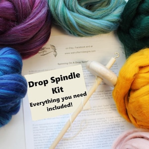 May include: A drop spindle kit with colorful wool roving in shades of purple, blue, green, and yellow. The kit includes a drop spindle and a card that reads "Drop Spindle Kit Everything you need included!"