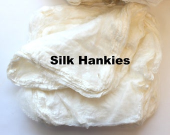 May include: A stack of off-white silk hankies. The fabric appears soft and delicate, with visible folds and textures. The text "Silk Hankies" is printed in black across the image. The hankies are neatly arranged, suggesting they are ready for use or sale.