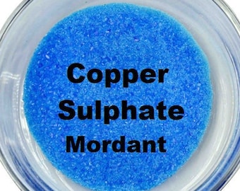 May include: A small clear container filled with bright blue copper sulphate crystals. The label reads "Copper Sulphate Mordant".