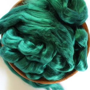 May include: A bowl filled with emerald green silk fiber. The fiber is soft and fluffy, and it is perfect for spinning or felting.