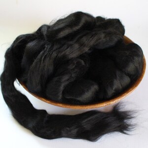 May include: A bowl filled with black alpaca fiber. The fiber is soft and fluffy, and it is perfect for spinning or felting.