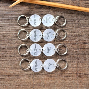 May include: Four sets of silver knitting stitch markers with clear plastic discs. Each set has two discs with the words "inc" or "dec" on one disc and "K" or "P" on the other disc.