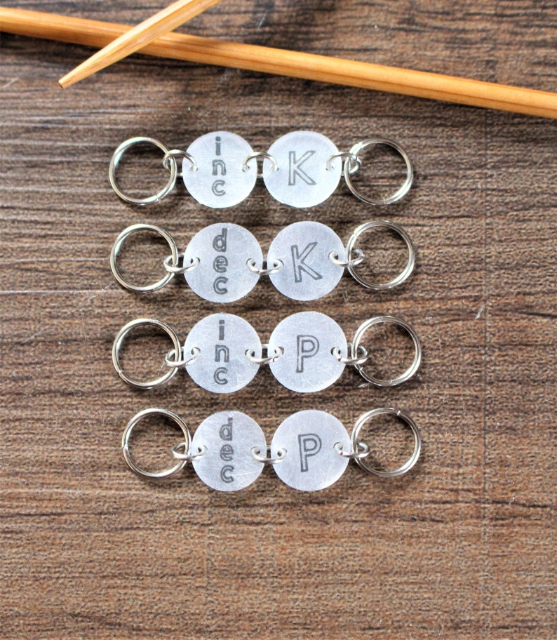 May include: Four sets of silver knitting stitch markers with clear plastic discs. Each set has two discs with the words "inc" or "dec" on one disc and "K" or "P" on the other disc.
