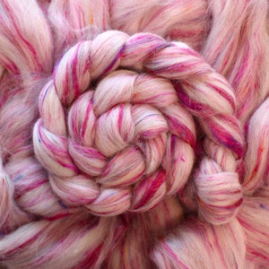 Puede incluir: Primer plano de un hilo rosa y blanco con motas de colores. El hilo est&aacute; trenzado en forma de espiral.
