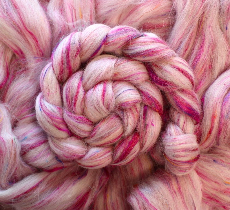 Puede incluir: Primer plano de un hilo rosa y blanco con motas de colores. El hilo est&aacute; trenzado en forma de espiral.