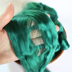 May include: A close-up of a deep green silk fiber, showing its soft and luxurious texture.