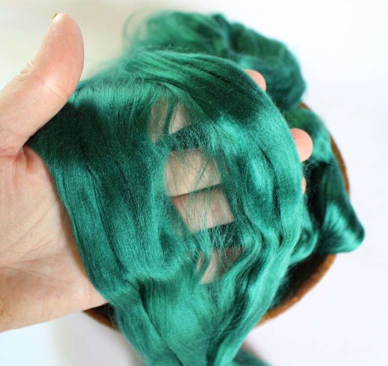 May include: A close-up of a deep green silk fiber, showing its soft and luxurious texture.
