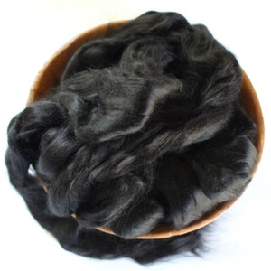 May include: A bowl filled with black silk fibers. The fibers are soft and fluffy, and they are perfect for spinning or felting.