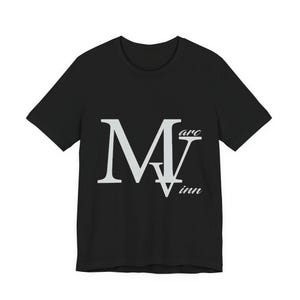 May include: A black short-sleeve t-shirt featuring a large, light gray graphic on the chest. The design consists of a prominent letter M overlapping a letter V, with the text Marc and inn written in a smaller, cursive white font.