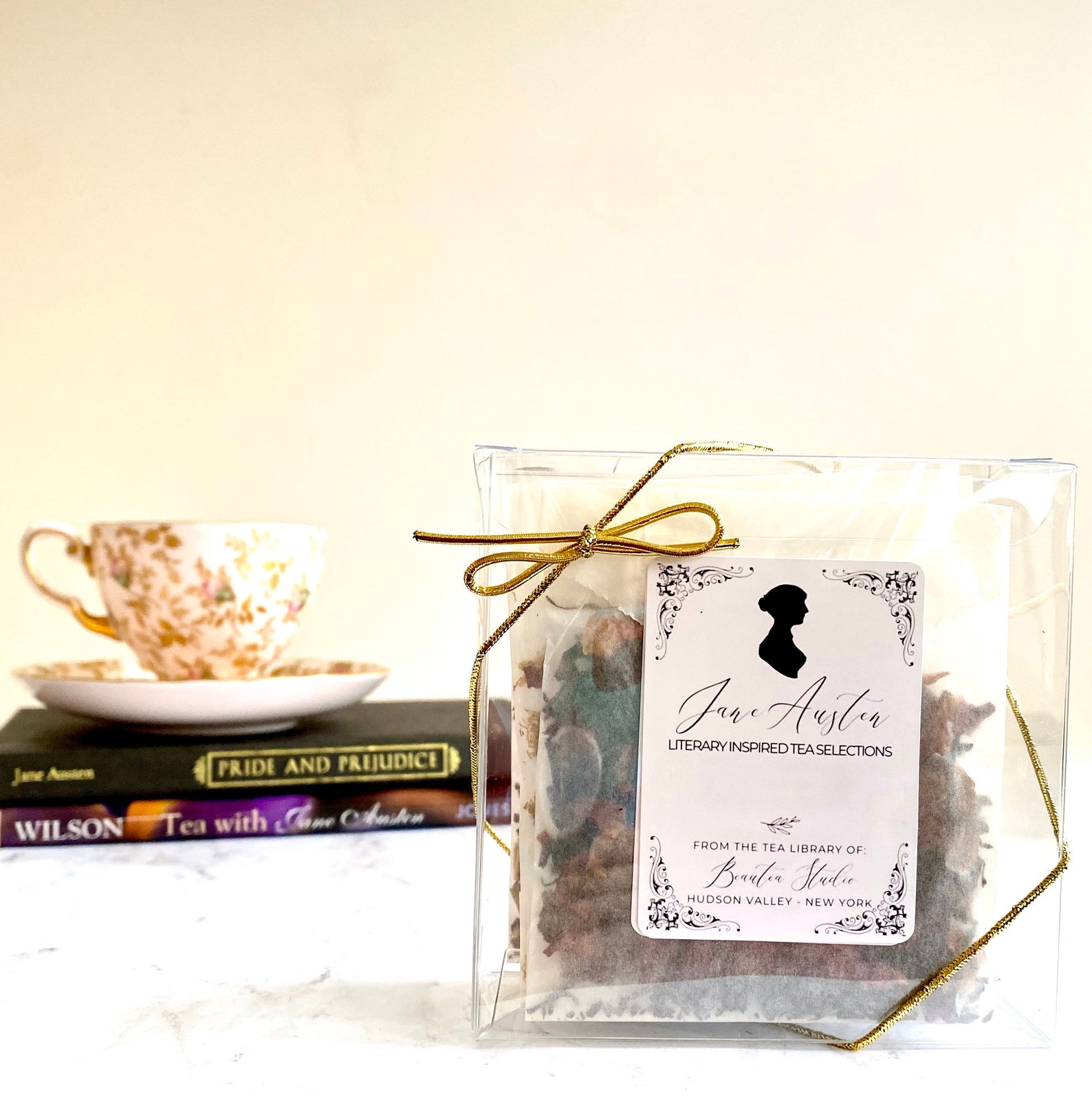a selection of tea labeled "Jane Austen Literary inspired Tea Selections" in the forefront, with a tea cup and saucer sitting on top of two books in the background 