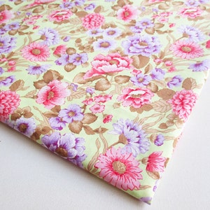 May include: A light green fabric with a floral pattern. The flowers are pink, purple, and brown. The fabric is soft and has a smooth texture.