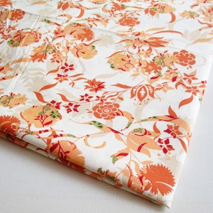 May include: White fabric with a floral pattern in shades of orange, red, and green. The fabric has a subtle sheen and a soft texture.