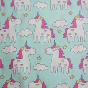 Puede incluir: Una tela turquesa con un patrón repetido de nubes blancas y unicornios rosas con corazones rosas y ojos azules. Los unicornios tienen una melena rosa y un cuerno azul.