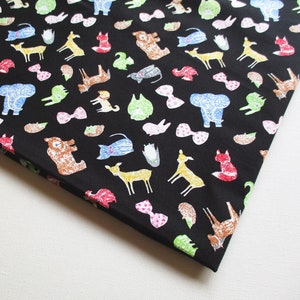 May include: Black fabric with a repeating pattern of colorful animals, including foxes, deer, bears, elephants, and birds. The fabric also features a repeating pattern of colorful bows.